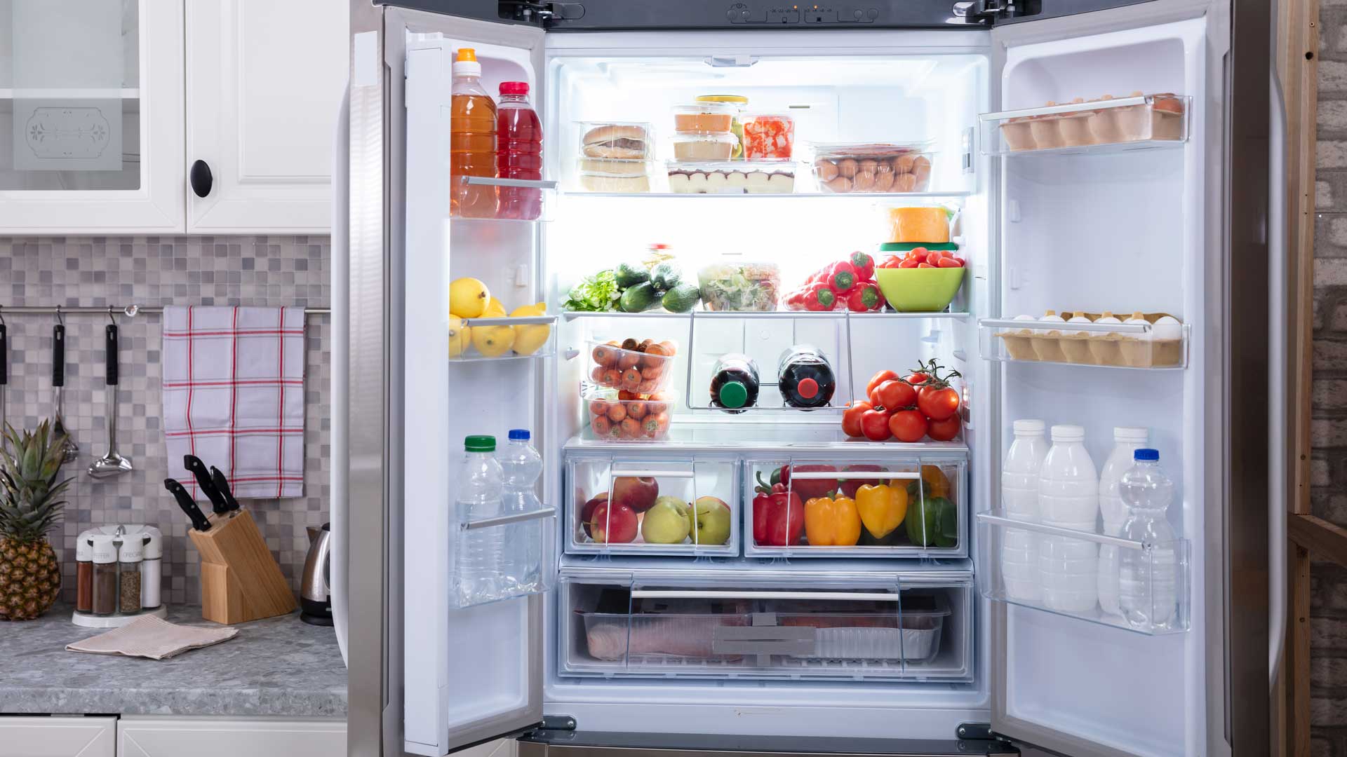 Refrigerator with open doors, full of fresh produce